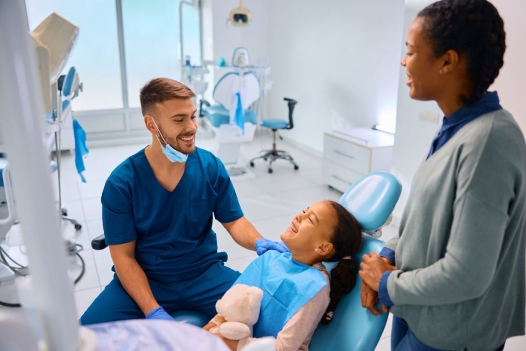 Dentist and assistant reassuring young patient in modern dental office during treatment.